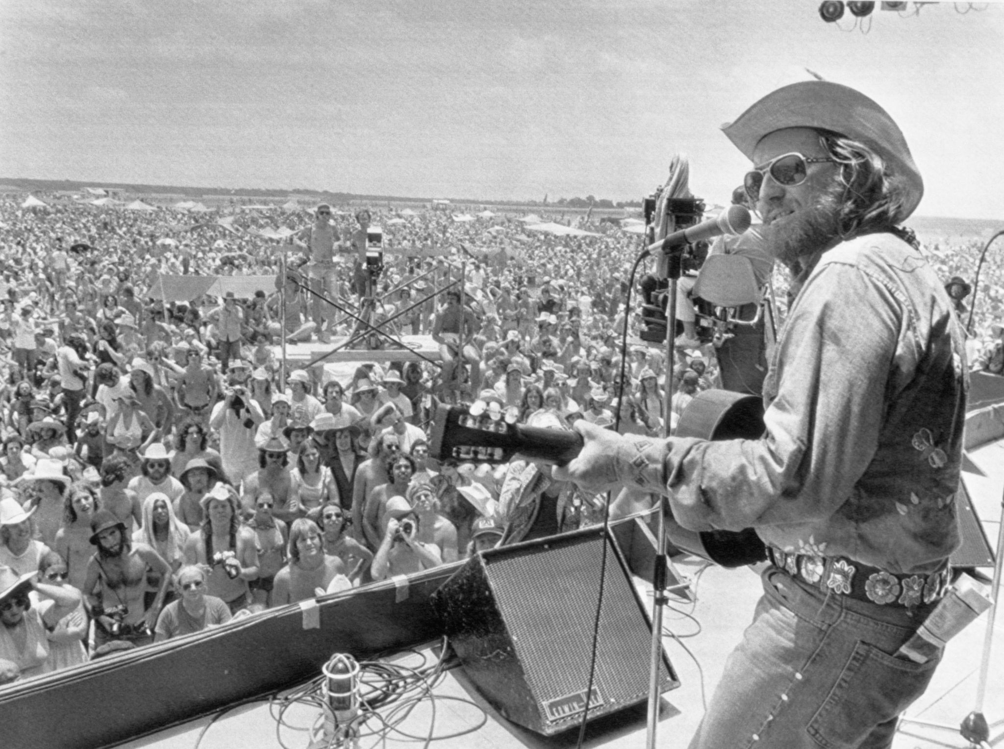 Willie Nelson performing before a large crowd at the 1975 picnic