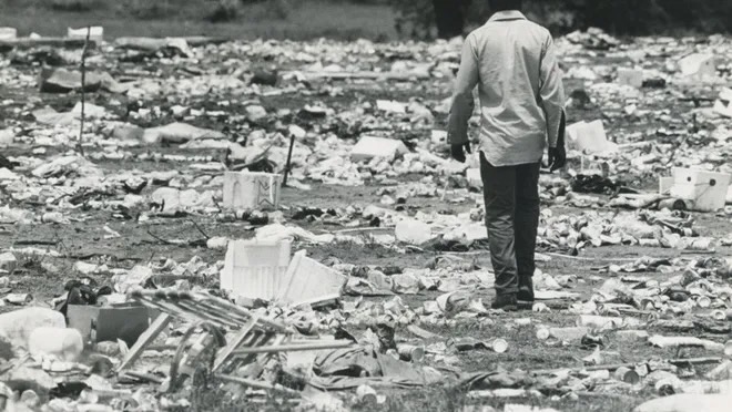 Man walking through a field full of trash after the picnic